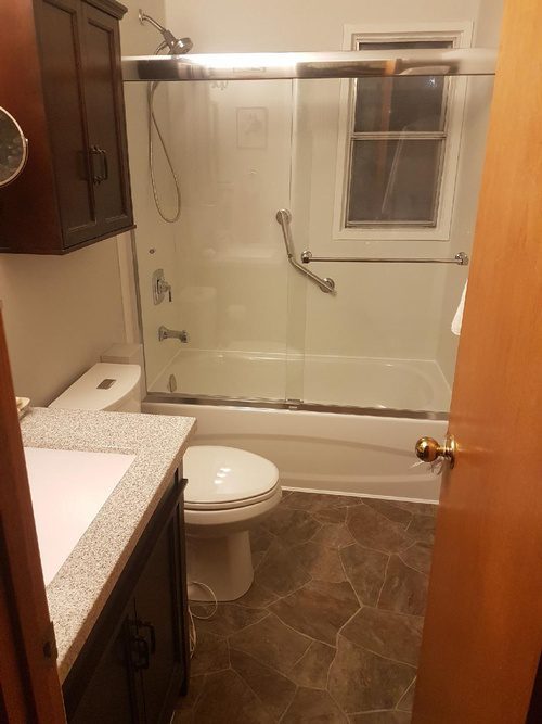 Stone floorings, brown cabinets, and a new shower area for a bathroom renovation project