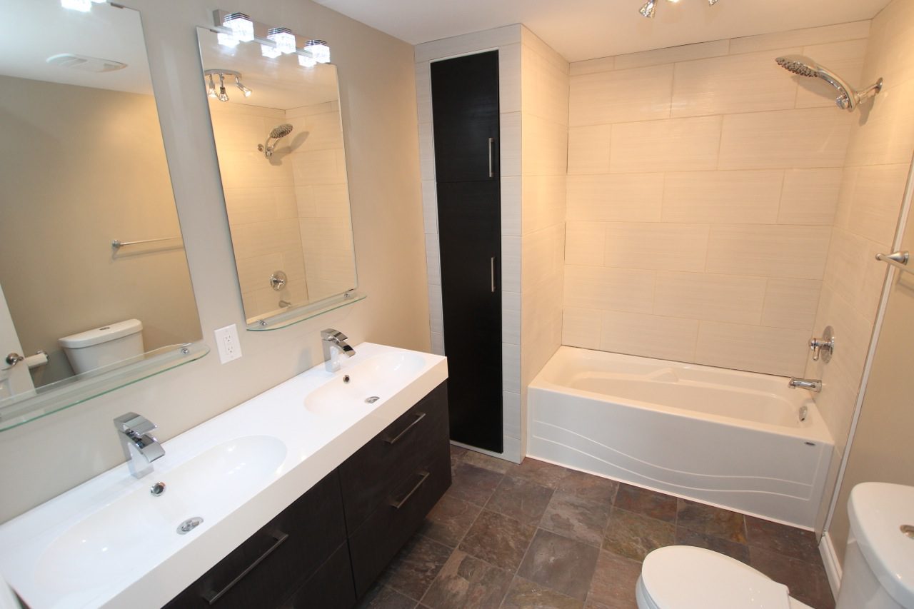 Dual sinks, mirrors, and a stone flooring for a bathroom renovation project